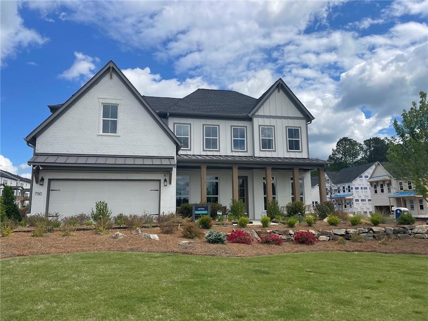 View of front of property with covered porch, a front yard, a standing seam roof, an attached garage, and board and batten siding