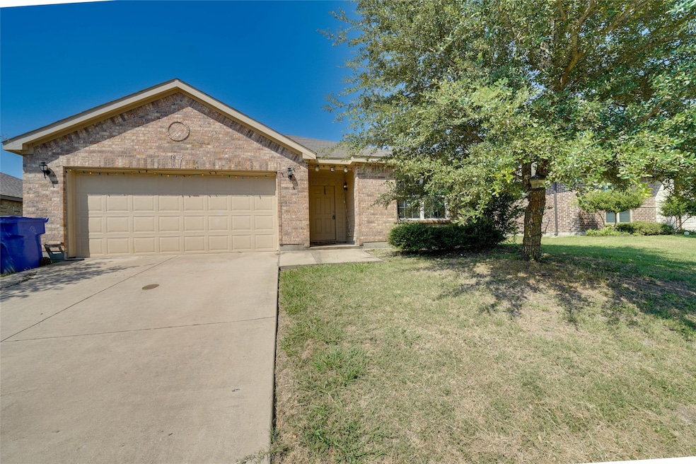 Ranch-style home featuring a garage, concrete driveway, brick siding, and a front lawn
