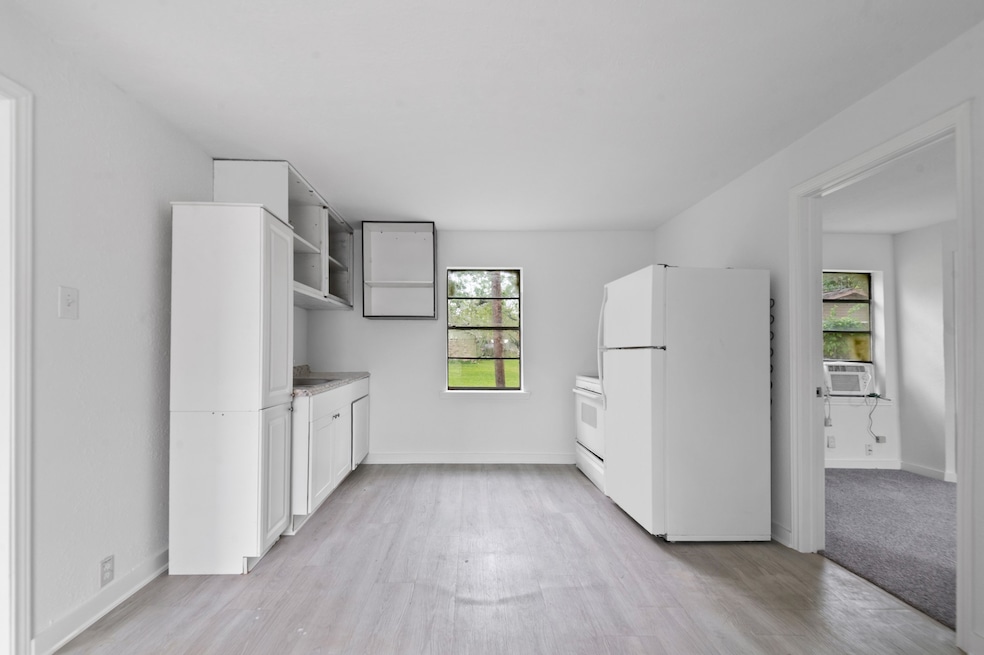 Bright, compact kitchen with white cabinetry, a re