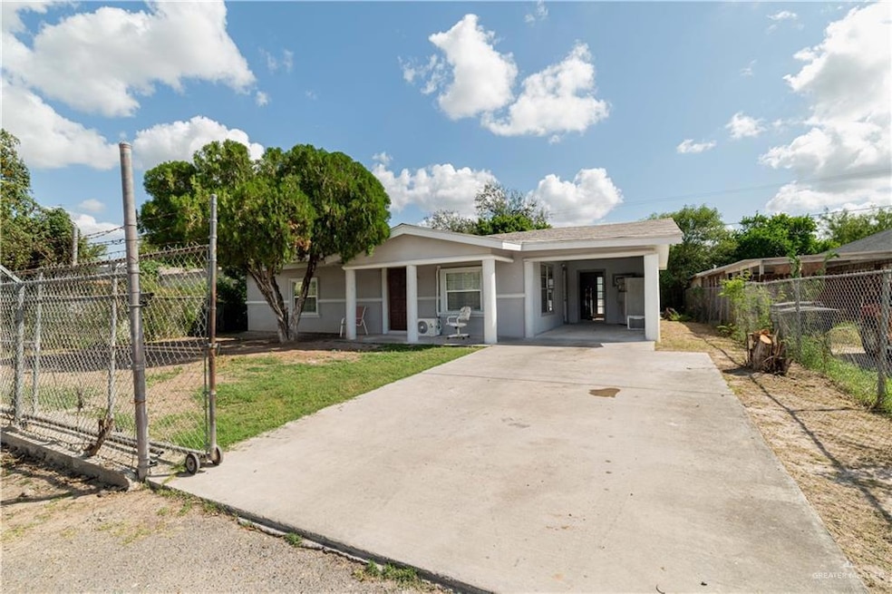 Ranch-style house featuring an attached carport, fence, stucco siding, a gate, and driveway