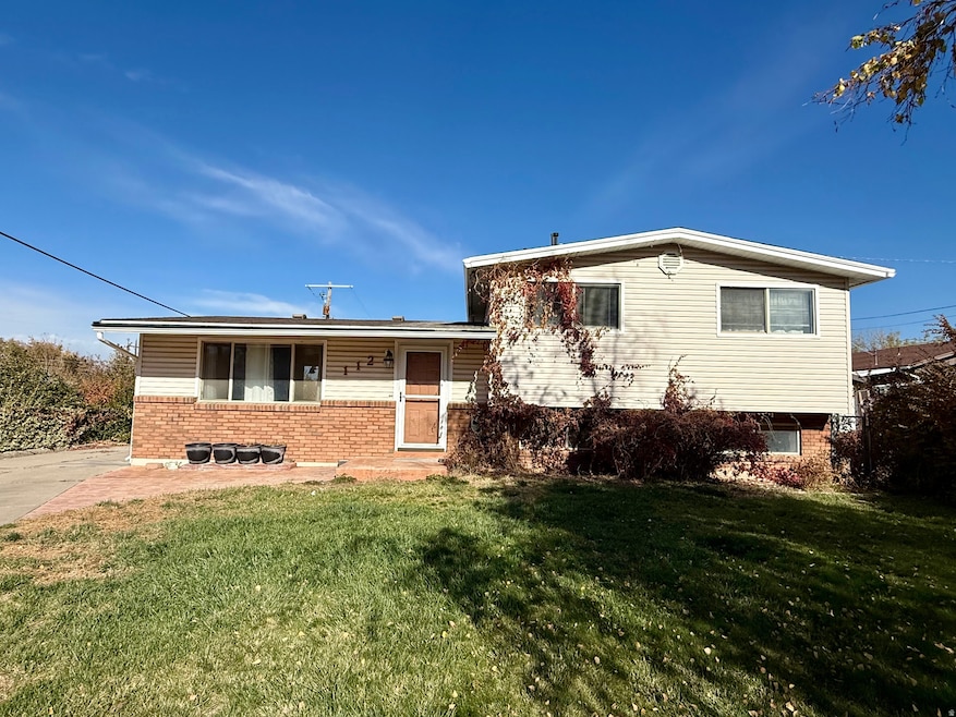 Tri-level home featuring brick siding, a front lawn, and a porch