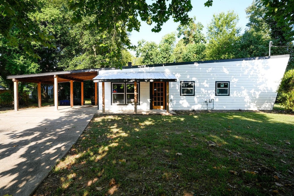View of front facade featuring a front yard, a patio, driveway, and a carport
