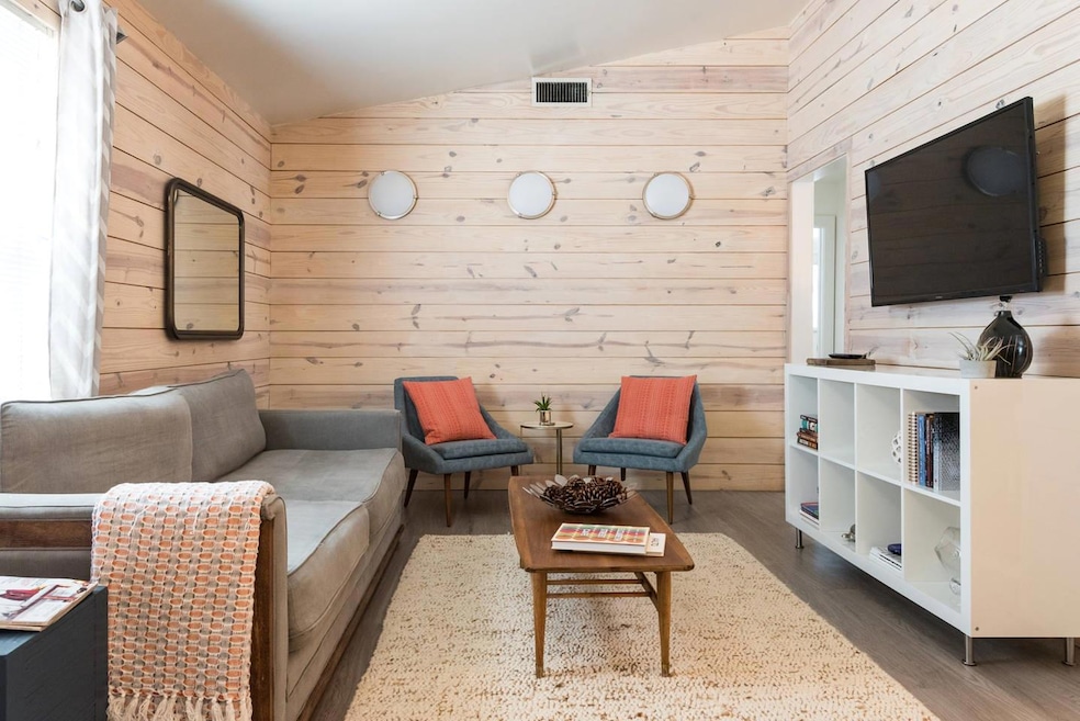 Living room featuring wooden walls, vaulted ceili