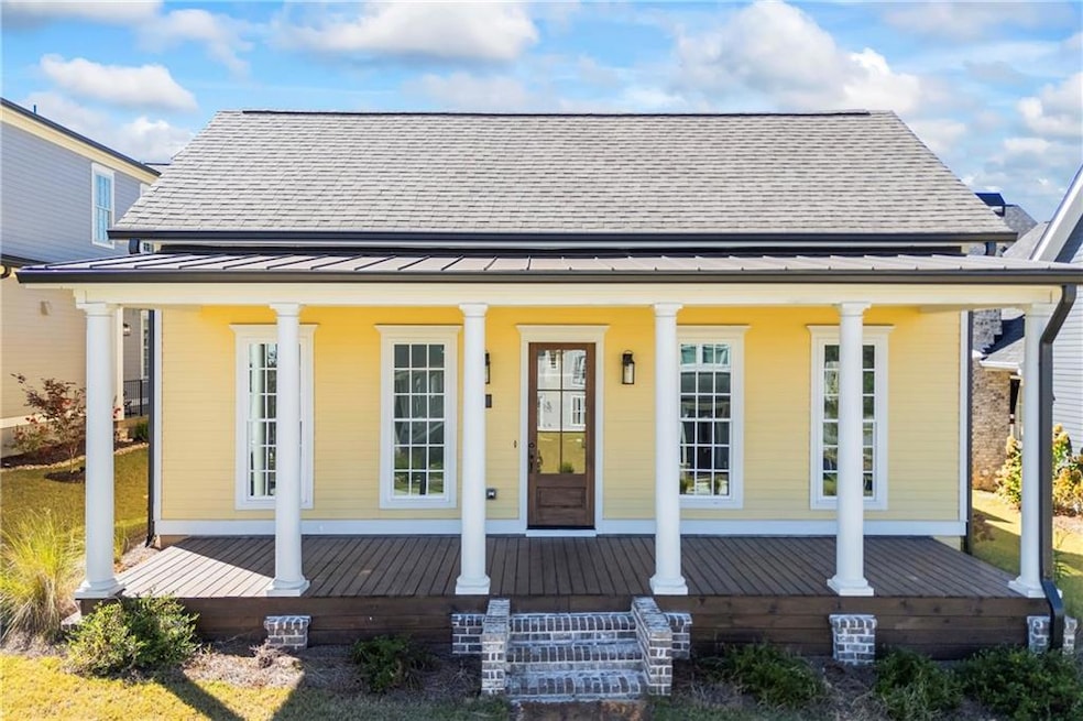 Back of property featuring covered porch, a standing seam roof, a shingled roof, and a metal roof