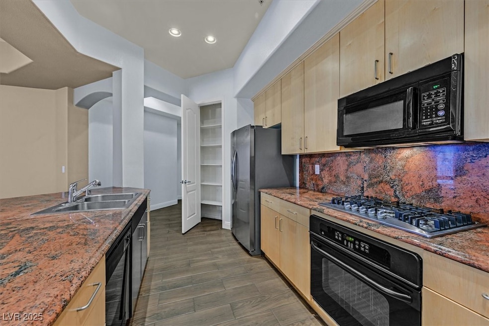 Kitchen with a sink, black appliances, and light b