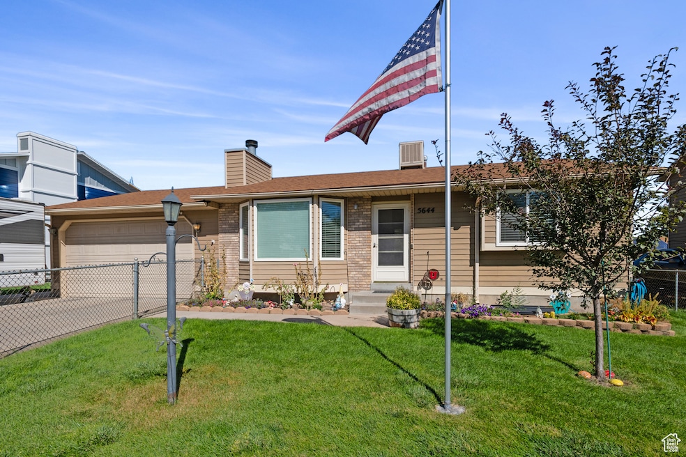View of front of property with concrete driveway, an attached garage, a chimney, brick siding, and roof with shingles