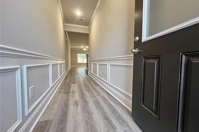 Hallway with crown molding and wood finished floors
