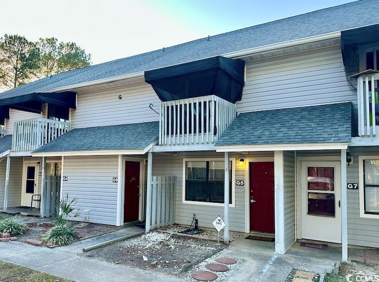 Multi unit property featuring a balcony and roof w