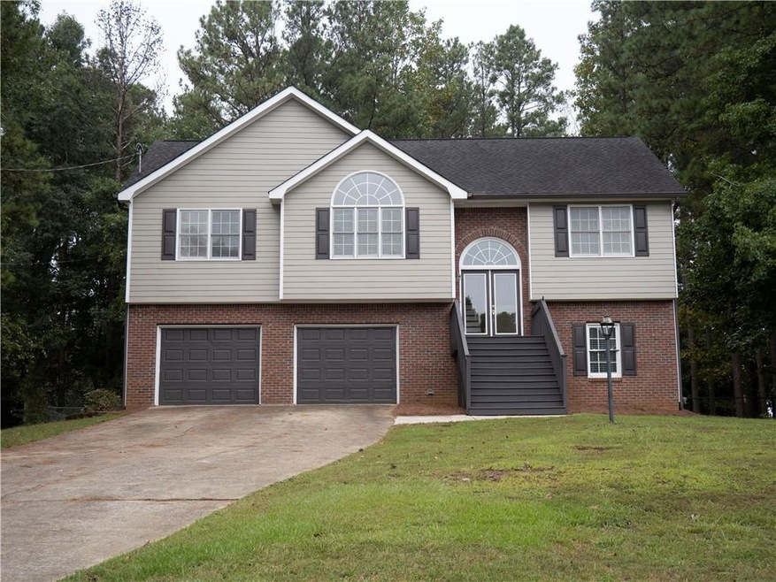 Raised ranch featuring a garage and a front lawn
