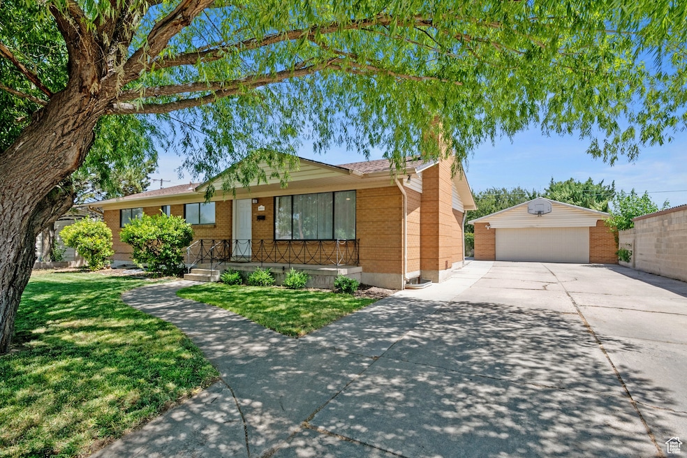Ranch-style house featuring an outdoor structure, brick siding, a garage, and a front lawn