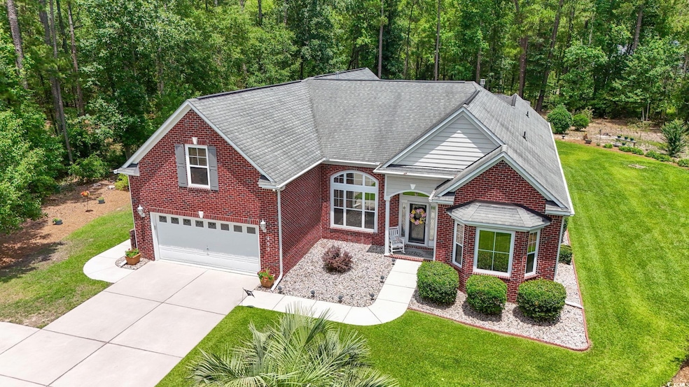 Traditional home with a garage, brick siding, driveway, a front yard, and a shingled roof