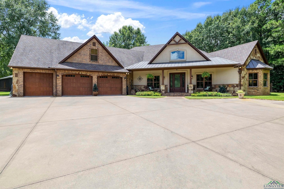 View of front of house featuring a porch, an attached garage, driveway, stone siding, and stucco siding