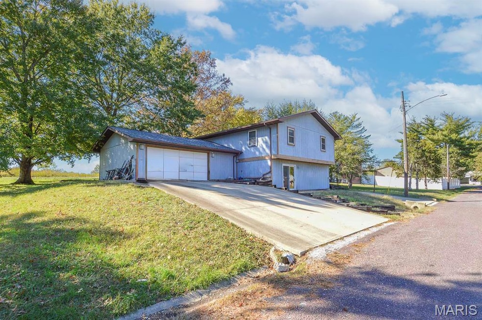 View of front of home featuring a garage, concrete driveway, and a front yard