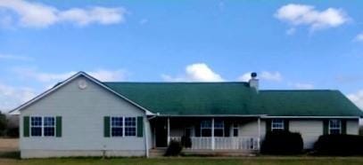 View of front of home with a porch, a chimney, and
