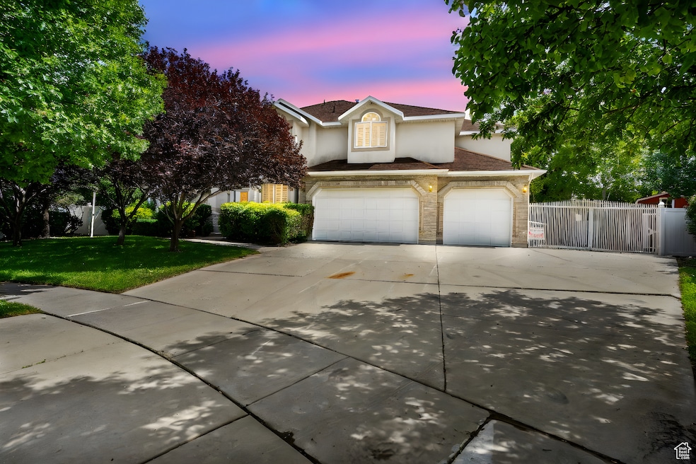 Traditional-style home featuring driveway, stucco siding, stone siding, and a garage