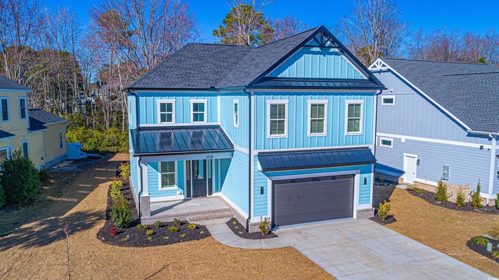 View of front of property with a standing seam roof, covered porch, driveway, and roof with shingles