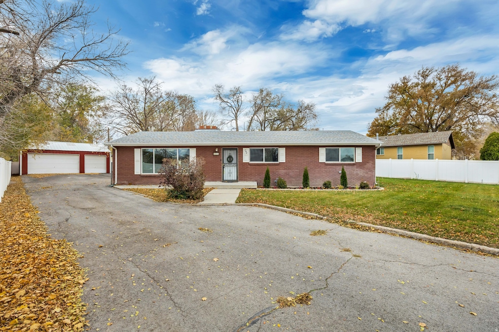 Ranch-style house with a garage, brick siding, an outdoor structure, and a chimney