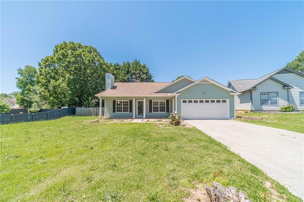 Single story home featuring an attached garage, a chimney, and driveway