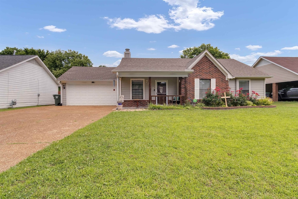 View of front facade featuring covered porch, a chimney, an attached garage, a front yard, and driveway