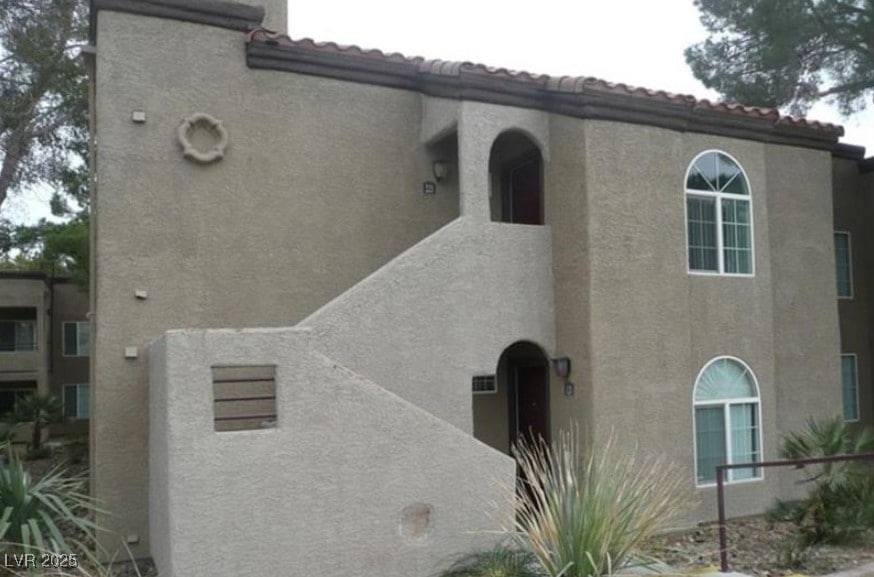 View of property with stucco siding and a tile roo