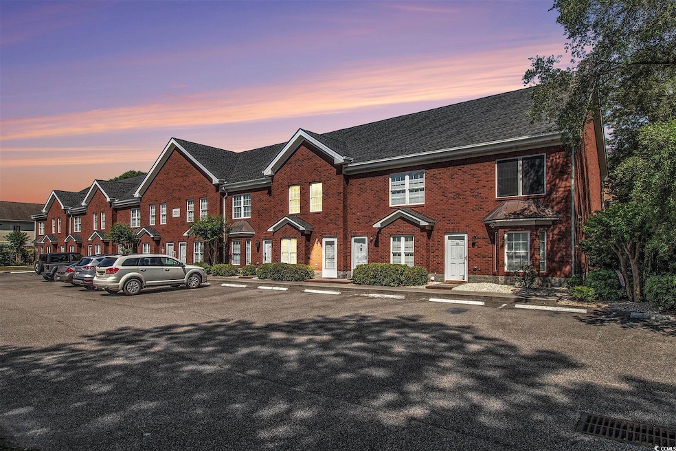 View of property with uncovered parking and brick 