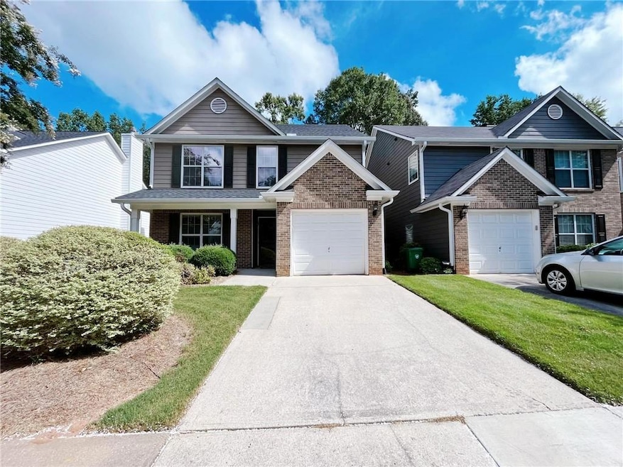 View of front of home featuring a front yard, brick siding, and concrete driveway