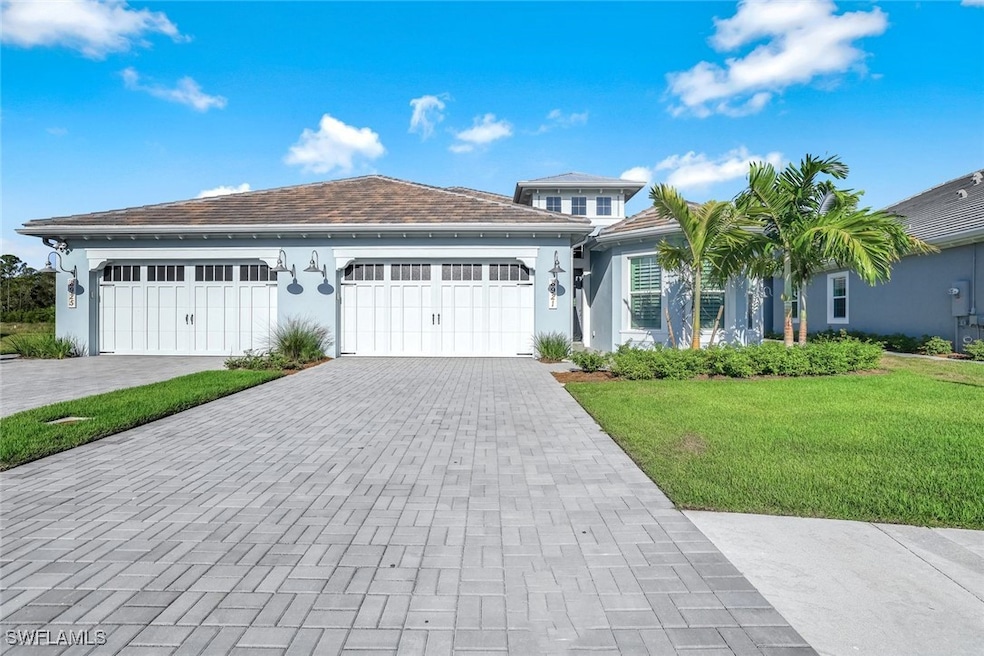 View of front facade with stucco siding, decorative driveway, a front lawn, and a garage