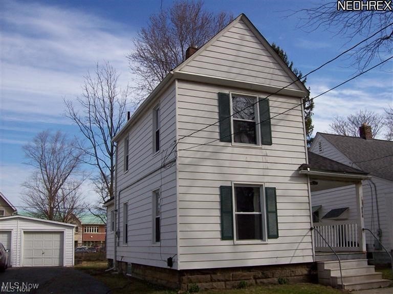 View of front of property with an outdoor structure and a detached garage