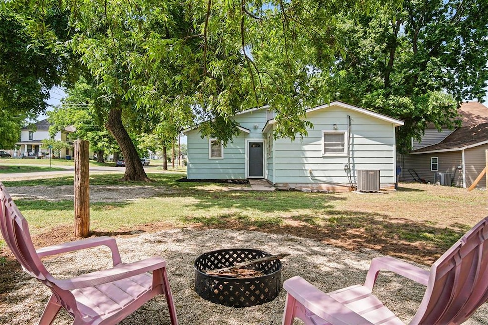 Rear view of property featuring a fire pit, central AC, and a yard