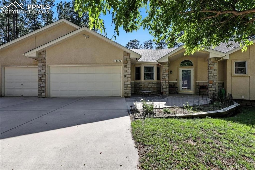 Single story home with stone siding, a garage, stucco siding, and driveway