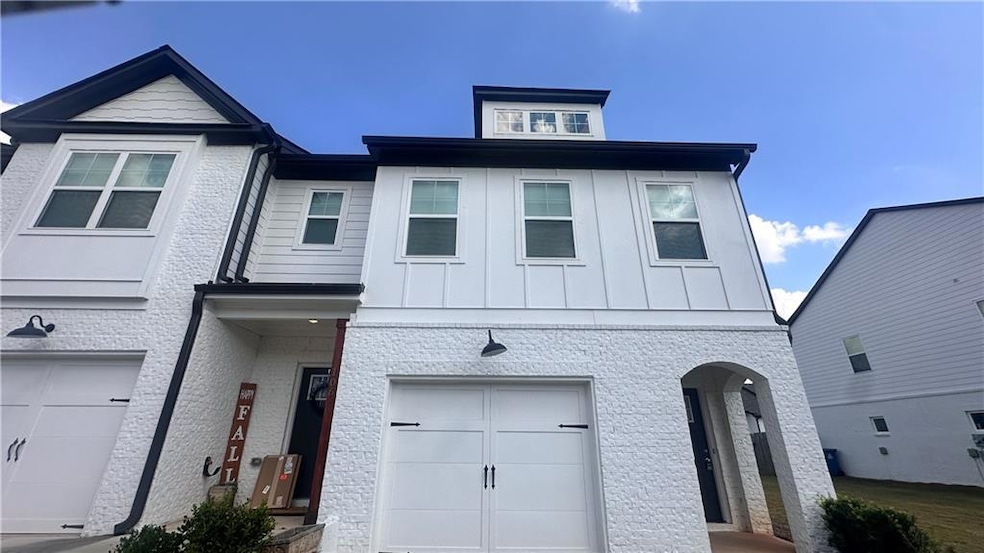 View of front of house featuring board and batten siding, an attached garage, and brick siding