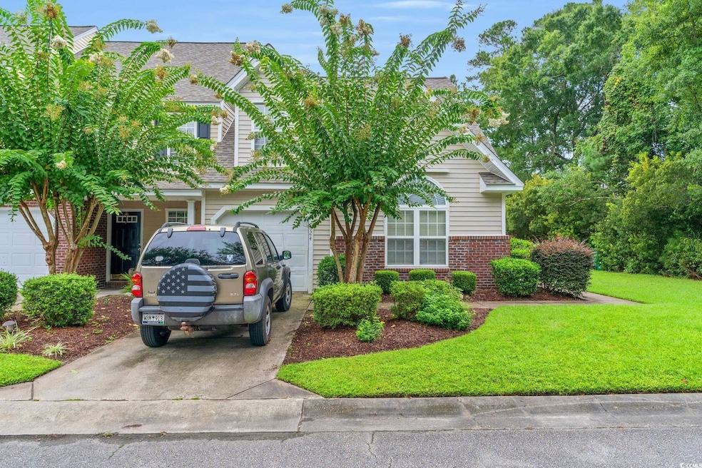View of front of home with driveway, brick siding, a shingled roof, and a front yard