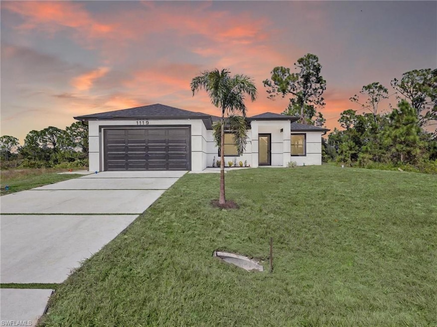 View of front facade with concrete driveway, a front yard, a garage, and stucco siding