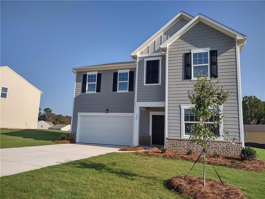 View of front of house with concrete driveway, an attached garage, a front yard, and board and batten siding