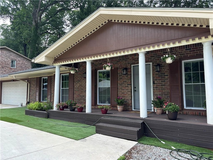 View of front of property featuring a porch, brick siding, and a garage