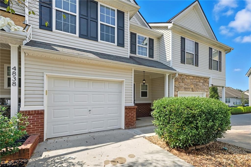 Traditional-style house featuring an attached garage, brick siding, a porch, and concrete driveway