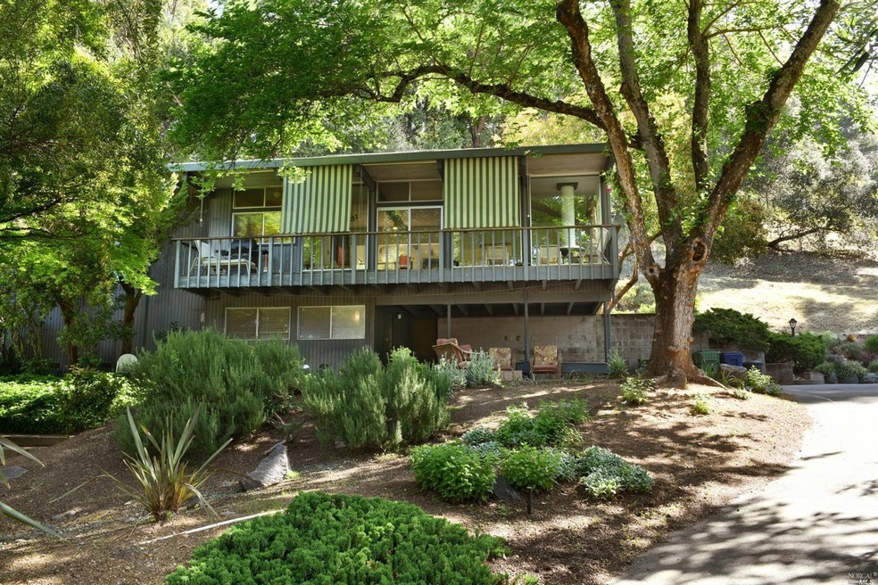 Front of home showing mature trees and landscaping