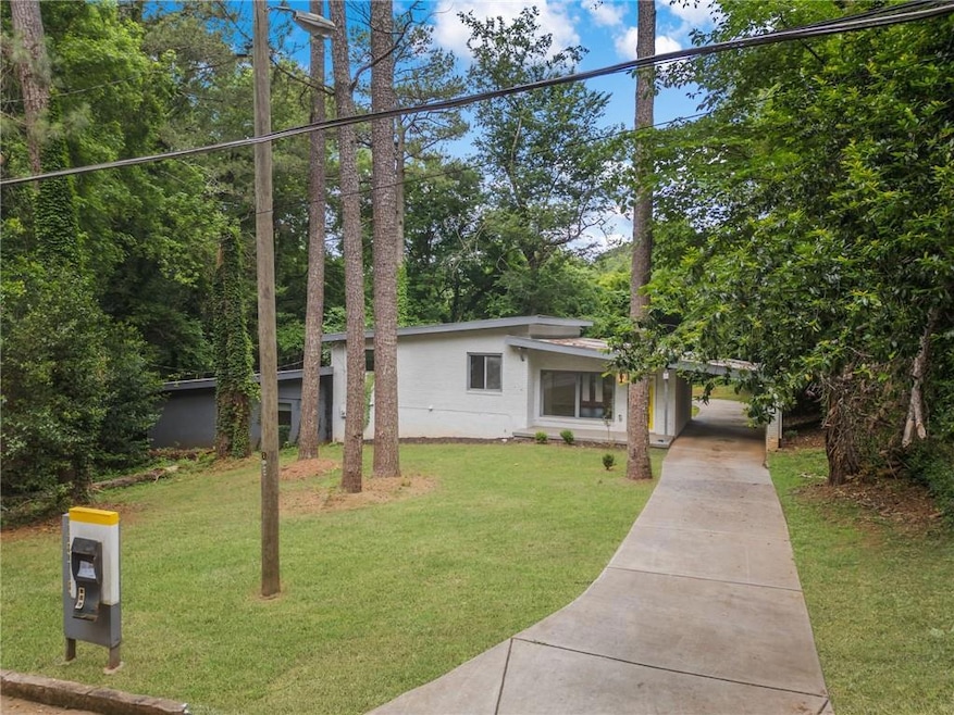 Mid-century home with concrete driveway, stucco siding, a front yard, and a carport