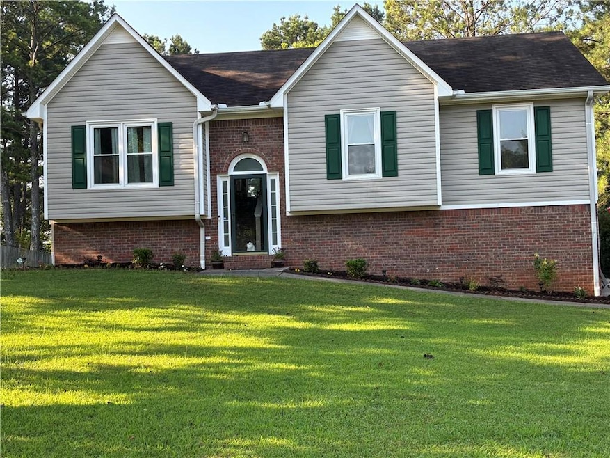 Raised ranch featuring brick siding and a front lawn