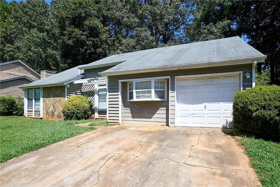Ranch-style home with concrete driveway, a garage, and a front lawn