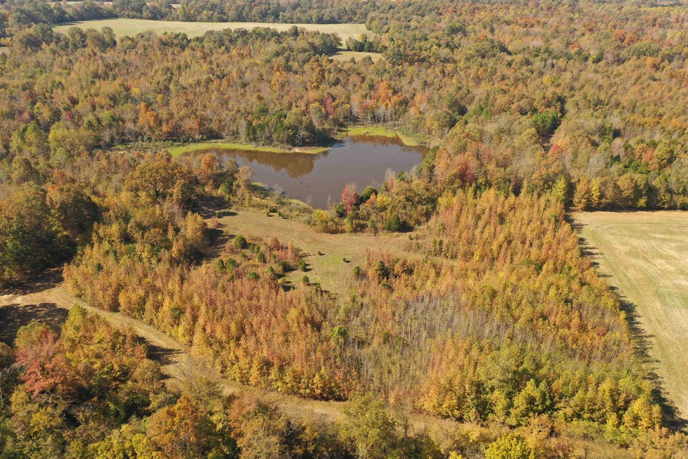 Aerial view of property and surrounding area with a heavily wooded area and a nearby body of water