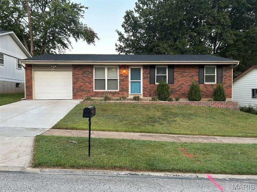 Single story home featuring concrete driveway, a front yard, a garage, and brick siding