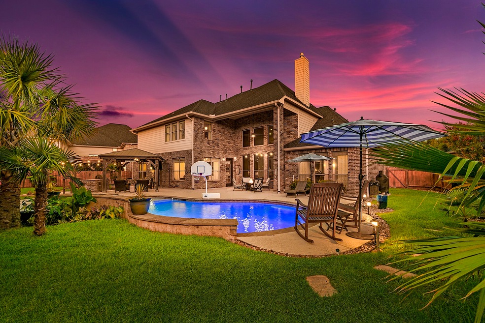 2410 Fairbreeze offers a backyard that rivals a resort, highlighted by a heated pool and spa. Surrounding the pool is cool decking and patio space, perfect for entertaining, complemented by lush landscaping. A pergola provides ample seating and space for hosting guests, with convenient access to a full bathroom featuring a stand-up shower for added comfort.

The large covered patio is equipped with an outdoor kitchen and grill setup, enhancing the outdoor dining and entertainment experience.