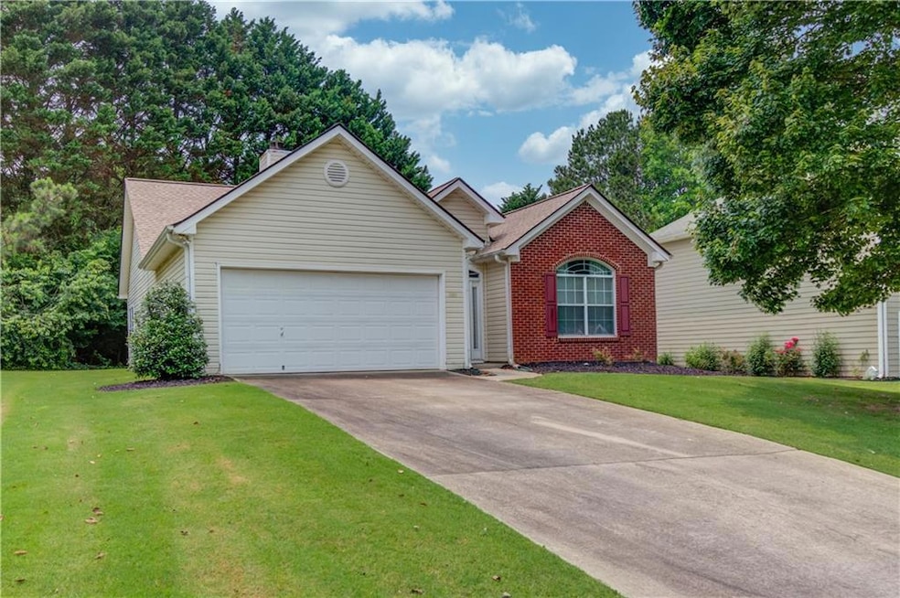 Ranch-style home featuring a garage, driveway, a front yard, and brick siding
