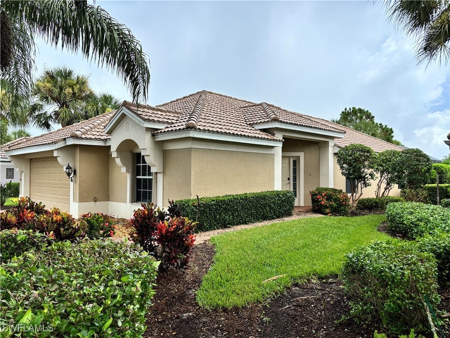View of front facade with an attached garage, stucco siding, a front lawn, and a tiled roof
