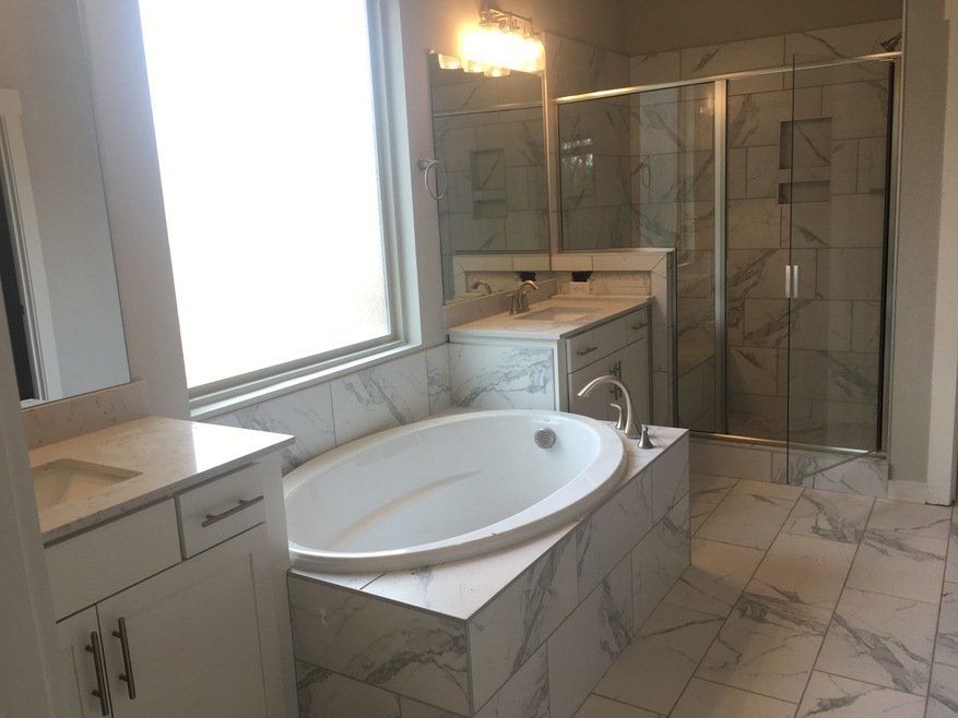 Luxurious tiled separate soaker tub and walk in shower in the master bathroom with tall double vanities with quartz countertops!