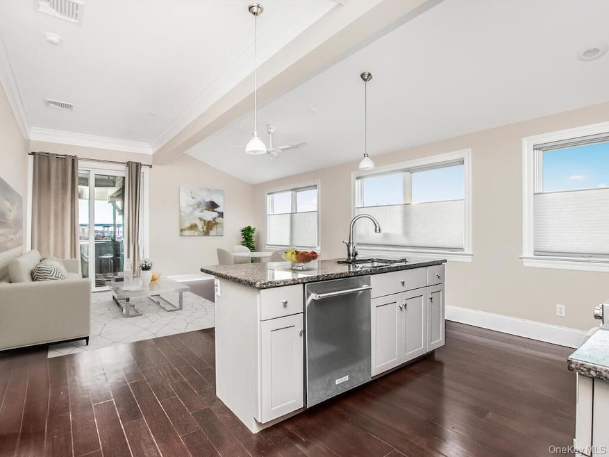 Kitchen with decorative light fixtures, dark stone counters, open floor plan, and healthy amount of natural light
