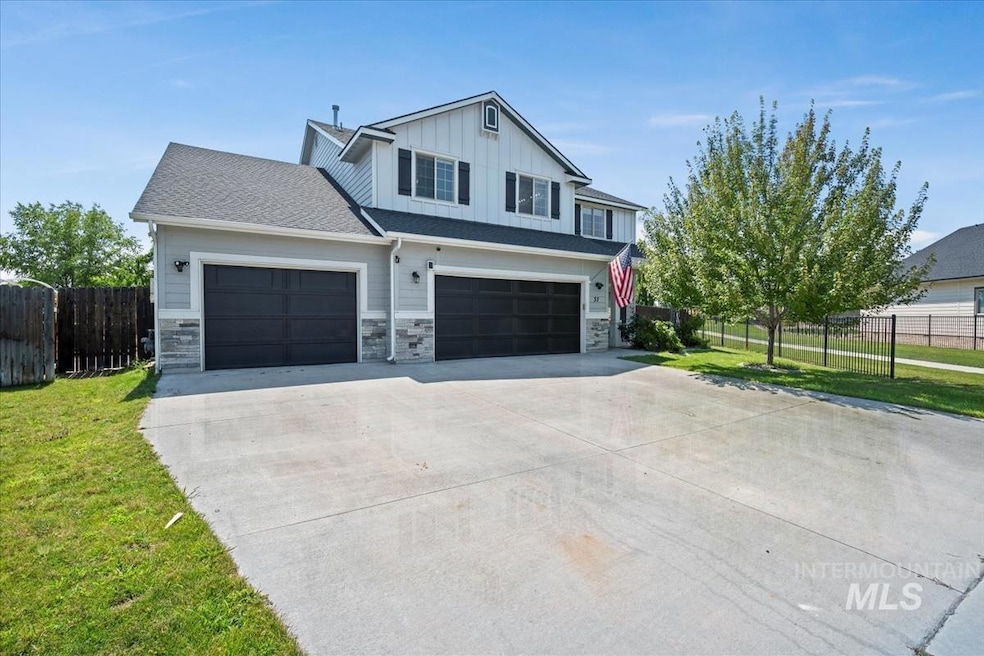View of front of house featuring driveway, stone siding, board and batten siding, and an attached garage