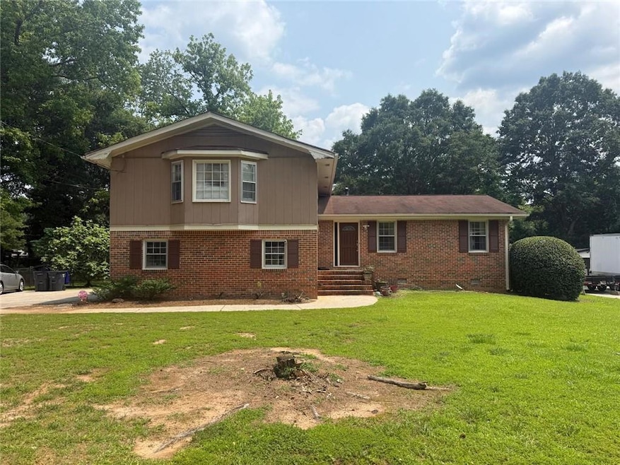 Split level home with a front yard, brick siding, and crawl space