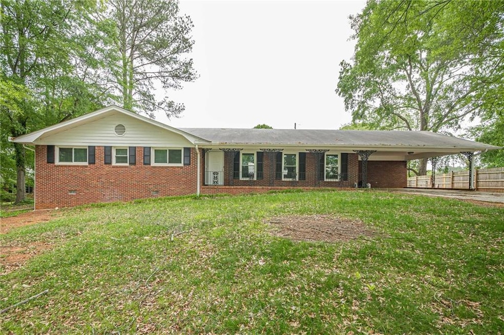 Ranch-style house with crawl space, brick siding, a carport, and driveway
